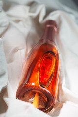 Wine bottle mockup with elegant design resting on soft fabric, showcasing rich amber color and unique shape, ideal for branding and marketing concepts