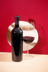 Red wine bottle mockup with elegant glass of red wine, set against a vibrant red background, showcasing modern design and sophisticated ambiance for creative projects