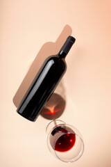 Wine bottle mockup with glass of red wine on soft peach background, showcasing elegant design and rich color, perfect for branding and marketing concepts