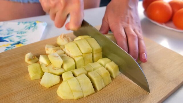 Woman chef hands cooking chopping eggplant into cubes on cutting board on kitchen. Culinary skills techniques, homemade prepare healthy meal, cook domestic food vegetable, cuisine, fresh ingredient.