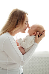 a mom with a baby, a mother holding a small newborn baby in her arms, kissing and gently hugging, happy motherhood, a family with a small child