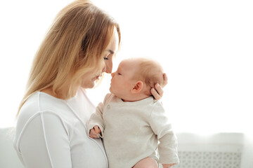 a mom with a baby, a mother holding a small newborn baby in her arms, kissing and gently hugging, happy motherhood, a family with a small child