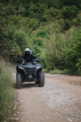 Two individuals enjoy a thrilling ATV ride together down a scenic, wooded dirt path.