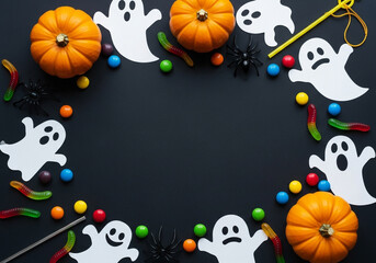 Halloween frame with pumpkins, ghosts, and candy on black background