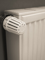 Warm toned photo of radiator thermostat and heating radiator