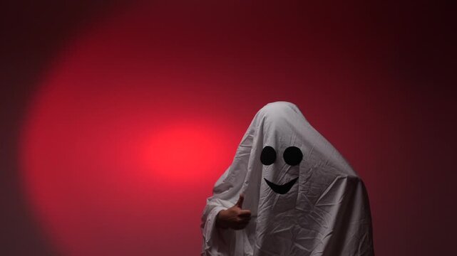 Halloween ghost costume giving thumbs up on red background