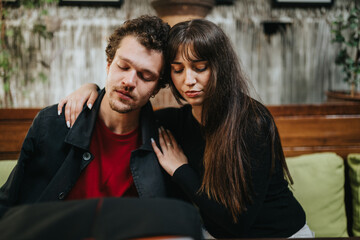 A young couple sitting closely together, depicting an intimate moment of support and emotional connection. They seem lost in thought, displaying a mix of contemplation and affection.