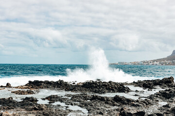 A view of a large wave crashing against the rocks.