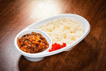 Japanese curry rice in plastic takeout container with pickles