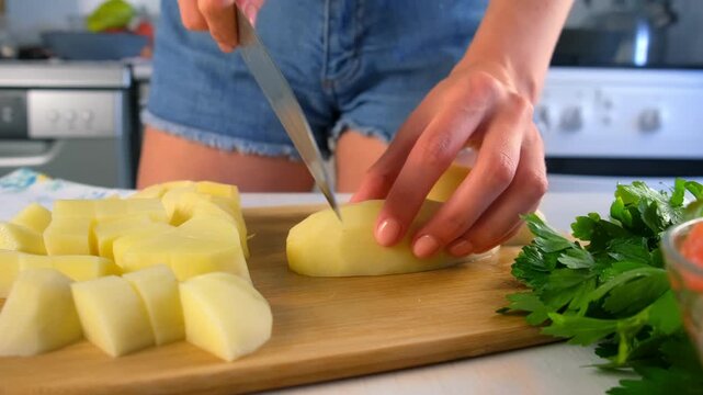 Chef woman hands cutting potatoes into cubes pieces on wooden board on kitchen. Culinary skills techniques, homemade preparing healthy meal, cook domestic food dish cuisine, fresh ingredient.