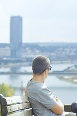 Belgrade skyline observation moment: man sitting on bench gazing at cityscape with modern tower and...