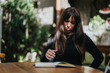 A young woman sits at a table in an outdoor area, expressing frustration or displeasure while...