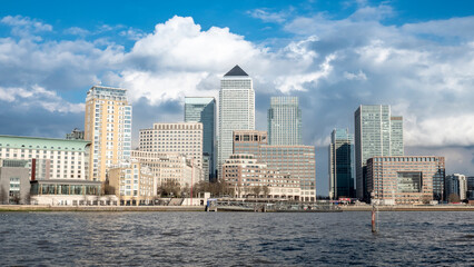Fototapeta premium Docklands, London. A detailed view of the Canary Wharf financial district skyline in East London, with the main towers prominent against a dramatic sky with the waters of the River Thames in front.