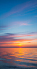 Fototapeta premium Stunning sunset over calm ocean water with vibrant colors reflecting on the surface, perfect for travel and relaxation