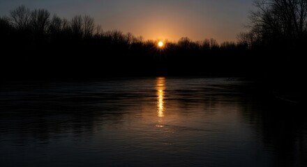 Obraz premium Golden sunset reflecting on a tranquil river surrounded by silhouetted trees