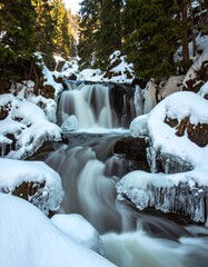 Obraz premium Winter waterfall cascading over icy rocks