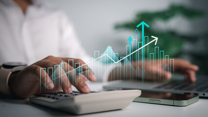 Business finance concept with hands using calculator and laptop, financial data growth graph overlay