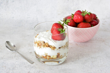 Strawberry Yogurt Parfait with Granola in a glass with a pink bowl of strawberries