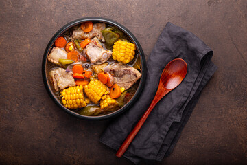 Chilean cuisine of Latin America. Traditional Chilean cazuela de cerdo. Pork soup with potatoes and corn, stew with corn and carrots on brown background top view