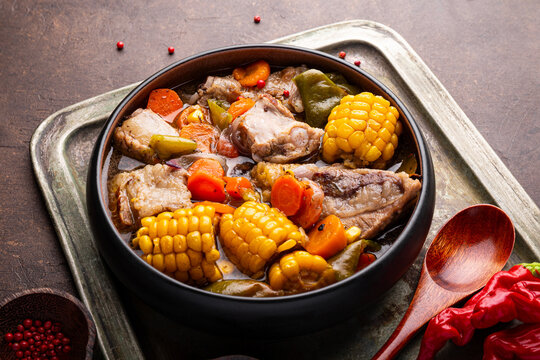 Chilean cuisine of Latin America. Traditional Chilean cazuela de cerdo. Pork soup with potatoes and corn, stew with corn and carrots on dark background