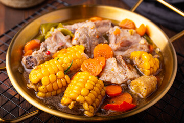 Chilean cuisine of Latin America. Traditional Chilean cazuela de cerdo. Pork soup with potatoes and corn, stew with corn and carrots on dark wooden background close up