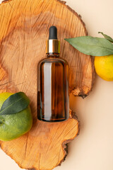 Natural eco-friendly cosmetics concept with vitamin C, citrus extract, facial serum, aroma oil. Brown glass cosmetic containers with pipette, fresh tangerines on wooden podium against beige background