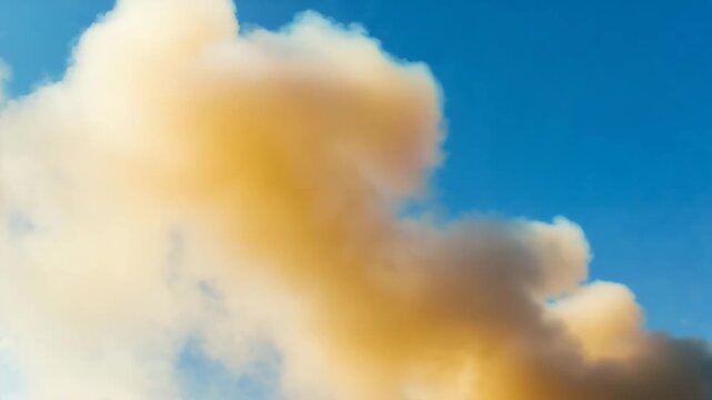 Dramatic wildfire smoke plumes billow against clear blue sky, a scene of nature's destructive power