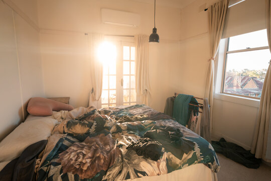 Bright sunlight entering messy bedroom through french door windows