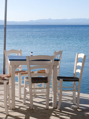 Kitries village, Mani Peninsula - Greece - September 21 2025 - Greek seaside taverna. View of the terrace with shadows cast by the late afternoon sun. View of bay over the blue Aegean sea.