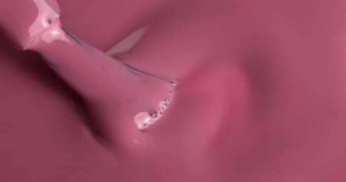 Liquid nail polish surface, pink nail polish is applied with a brush manicure concept, slow motion. Manicure salon, nail polish texture, background. Top view.