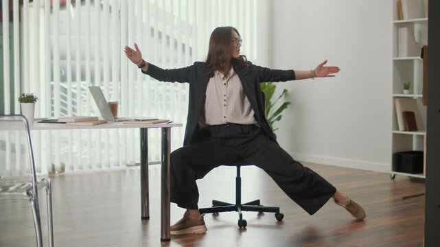 Office Ergonomics and Employee Wellness. Office Manager Performs Seated Side Leg and Lumbar Spine Stretch at Desk to Improve Flexibility, Support Posture, Reduce Discomfort and Promote a Balanced