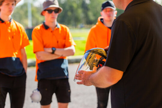 instructor holding face shield talking to trade apprentice students about hazards and safety PPE