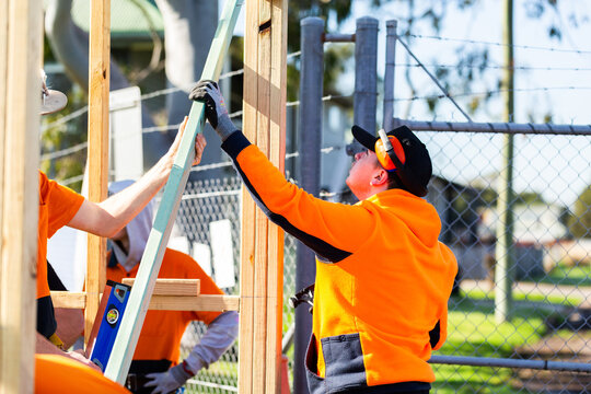 Trade apprentices working together securing temporary support structure to building frame