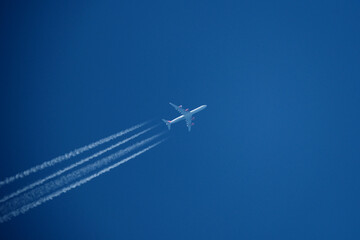 Airplane in the blue sky with contrail, closeup of photo. Airplane in the blue sky with white trace of a plane.