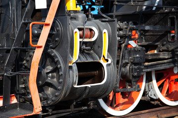 Large metal wheels of a steam locomotive transmitting traction from the locomotive to the rails, industry, close-up