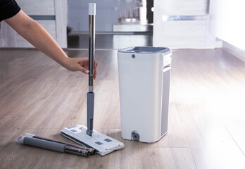 Washing and cleaning the room with a modern mop with a bucket and wringer. Modern novelty for cleaning. Copy space for text, automatic spin