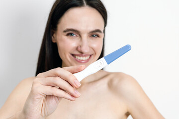 Young woman happily checking pregnancy test result at home