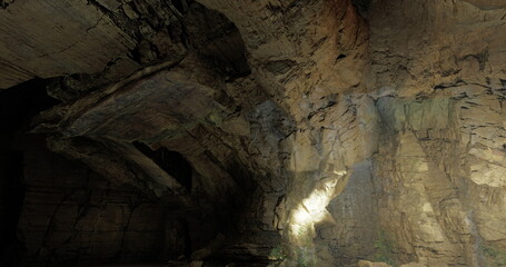 A breathtaking cave interior reveals stunning rock formations illuminated by soft light. The rugged texture and shadows create an atmospheric environment in this natural wonder.
