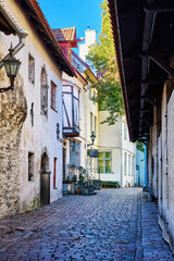 Medieval stone street with archways and rustic buildings in historic European town. Narrow cobblestone street with medieval stone walls, wooden doors and tiled archways in an old European town. 
