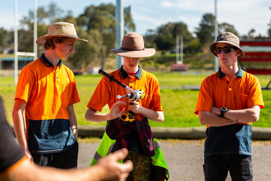 young trade apprentices at tool demonstration passing around drill