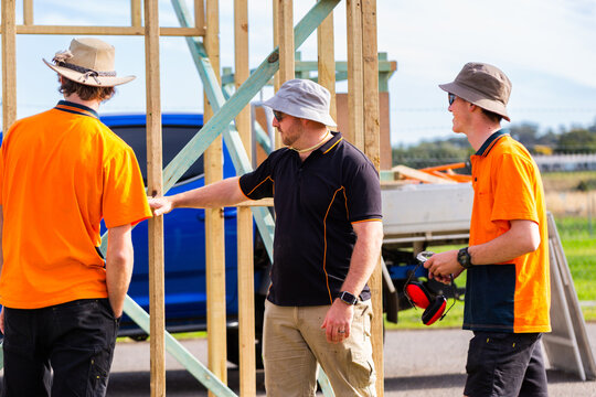 Trade instructor teaching students during hands on learning course building frame of ticket booth