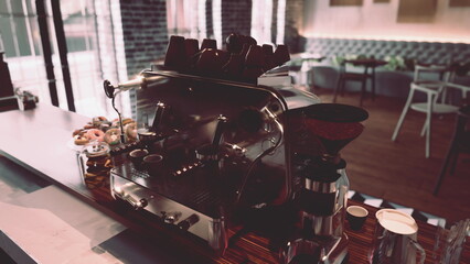 A modern coffee machine sits on top of a counter in a contemporary cafe interior.