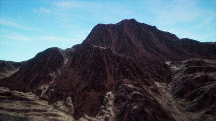 Breathtaking view of rugged mountains bathed in golden light during sunrise. The scenic beauty captivates with textured rocky surfaces and an expansive blue sky, inviting adventure.