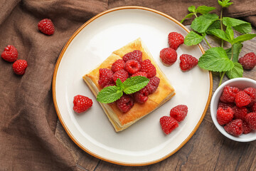 Yummy puff pastry with raspberries and mint on wooden table, flat lay