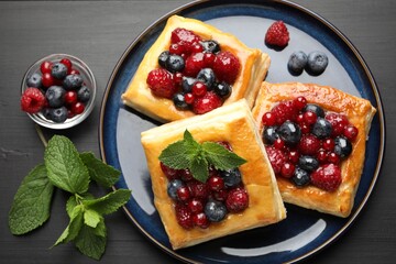 Tasty puff pastries with berries and mint on grey wooden table, flat lay