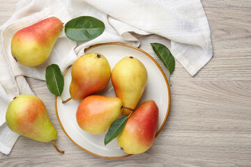 Fresh ripe pears and green leaves on wooden table, flat lay