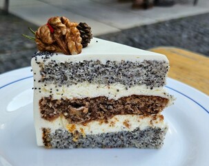 Poppy seed cake with buttercream. Delicious beautiful piece of cake decorated with cream and walnuts on a white plate