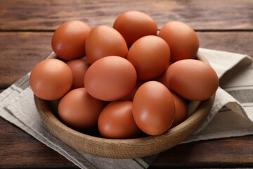 Raw chicken eggs in bowl on wooden table, closeup