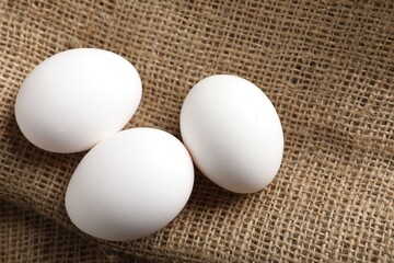Raw chicken eggs on burlap cloth, closeup