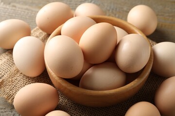 Raw chicken eggs in bowl on wooden table, closeup